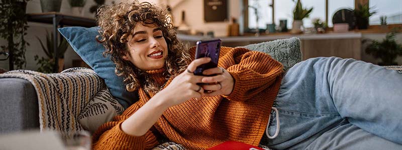 Mujer acostada en un sillón usando el celular