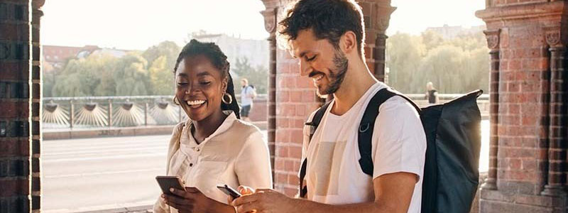 Hombre y mujer hablando mientras utilizan su teléfono