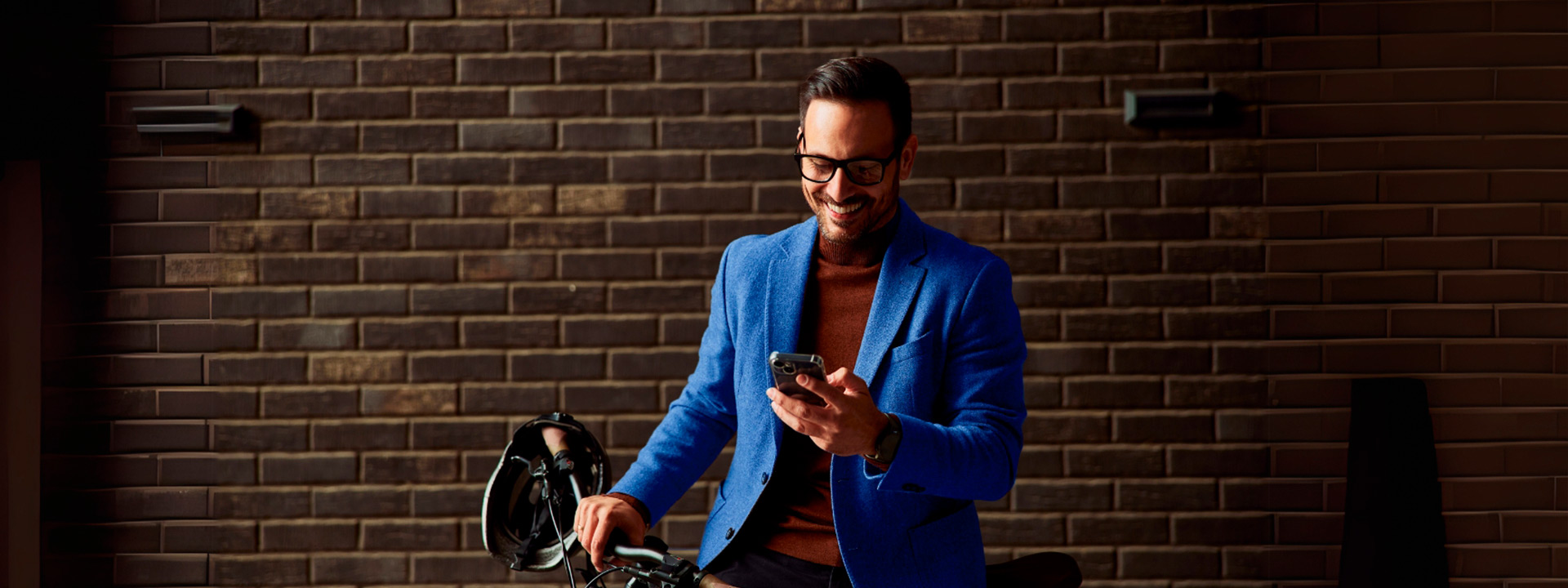 Hombre sonriente usando su celular sosteniendo su bicicleta